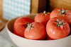 A bowl of ripe red tomatoes with green stems, placed on a kitchen counter.