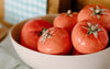 Bowl filled with round, ripe red tomatoes on a kitchen counter.