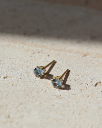 A pair of Token Jewelry December Birthstone Studs in 14K Gold Fill on a textured surface.