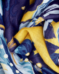 Close-up of a crumpled Inoui Editions Chatou Winter Scarf in Duck Blue, made with 100% Wool fabric and featuring a yellow, blue, and white floral pattern.