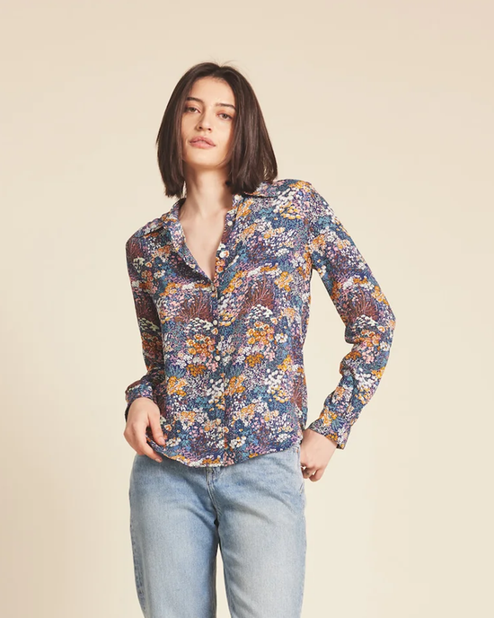 Woman posing in a button-down Trovata Birds of Paradis Jacquelin Shirt in Bijou Glade and jeans against a neutral background.