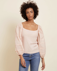 A woman wearing a pale pink Nation LTD Pima Cotton Emmeline Pintucked Top in Recital with a square neckline and blue jeans against a neutral background.