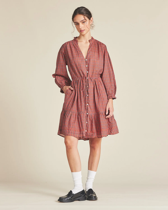 Woman modeling a plaid Trovata Birds of Paradis Yulia Dress in Redford Plaid with 2-tiered skirt and drawstring waist, paired with white socks and black shoes.