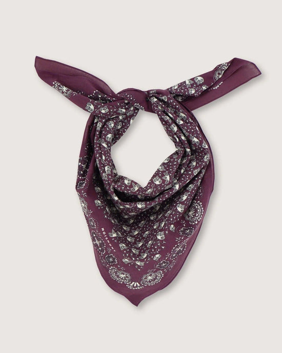 The Bandana No 675 in Plum by Moismont, crafted from cotton and adorned with a screen-printed white paisley pattern, is elegantly tied in a simple knot against a plain background.