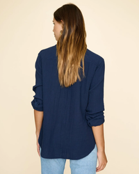 Woman from behind wearing a navy blue XiRENA Scout Shirt in North Star and denim jeans.