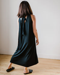 Woman walking in a room wearing a Velvet by Graham & Spencer Reeba Halter Maxi Dress in Black and black shoes.